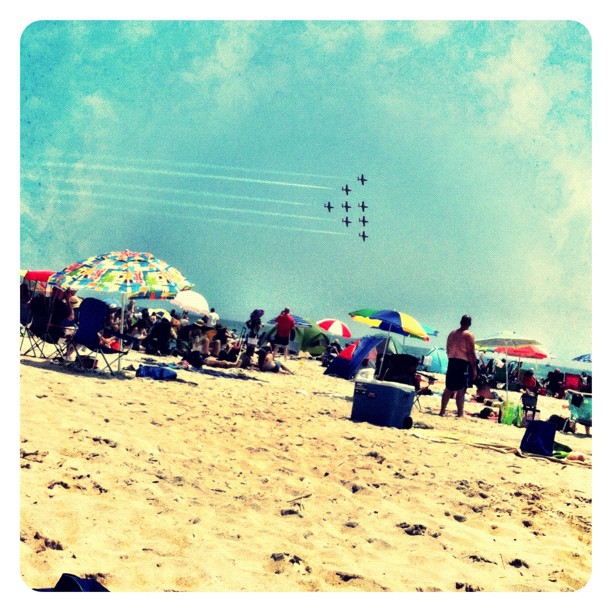 Beachgoers watch jet planes fly by in formation