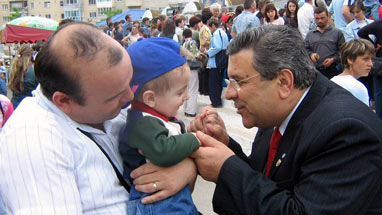 A child, being tenderly held by an adult, interacting with another man.