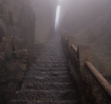 A stone exterior staircase, steeped in fog.